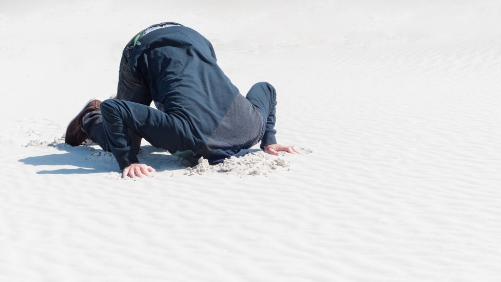 Young male hiding head in sand